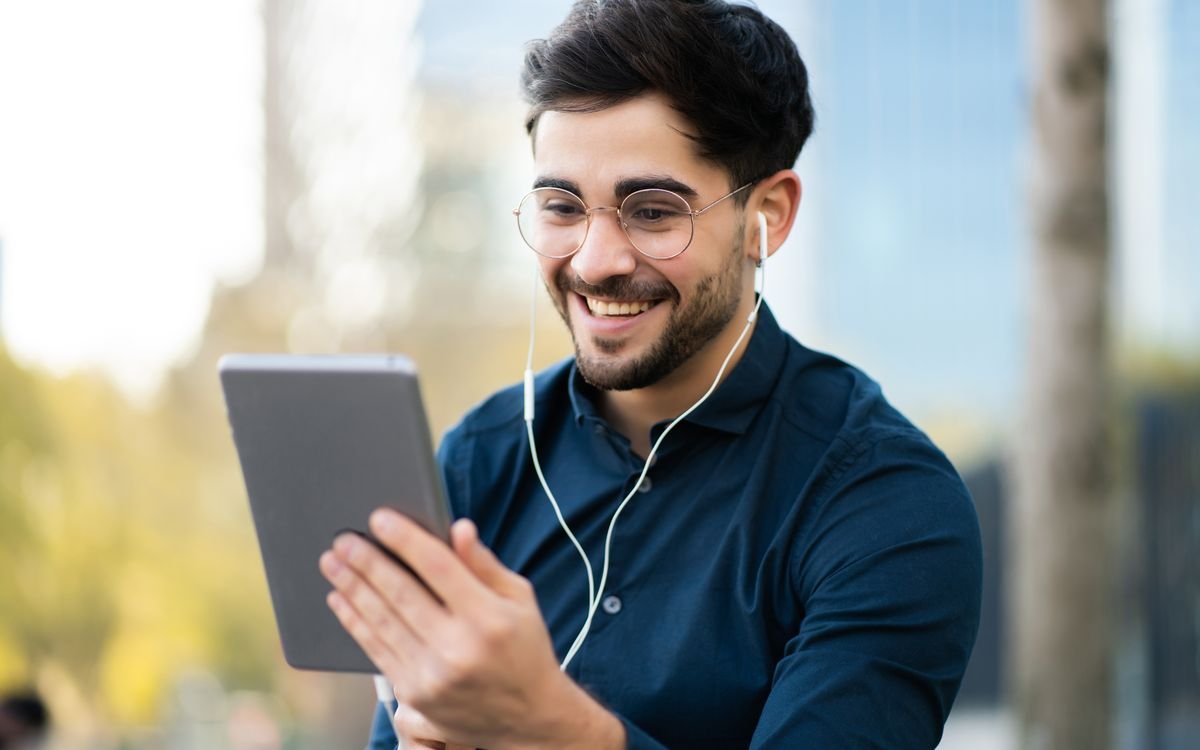 Homem sorrindo usando um tablet ao ar livre